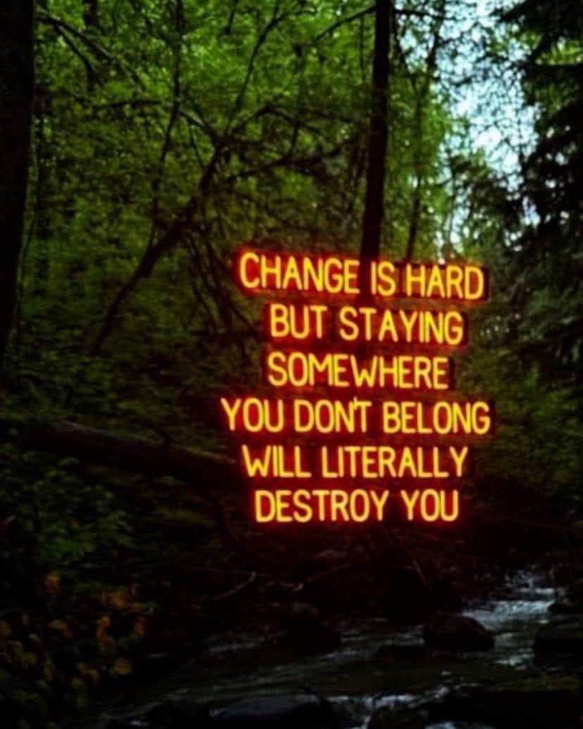 The meme is a humorous and darkly ironic image with the text: "Change is hard. But, staying somewhere you don't belong will literally destroy you." The image is likely a dark or eerie landscape, such as a forest or abandoned building, with the text appearing in a bold, neon-like font. The overall tone is meant to be humorous and satirical, poking fun at the idea that people often struggle with change, but also that staying in a situation that's not right for you can be disastrous.